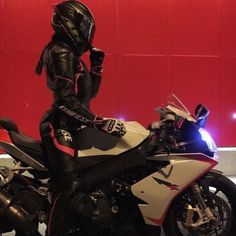 a man dressed in black and white is standing next to a motorbike on display