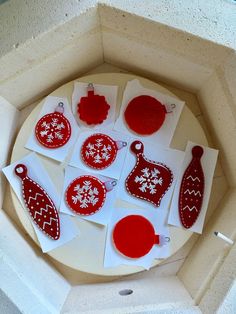 some red and white ornaments are sitting in a box on the table, with one ornament cut out to look like snowflakes