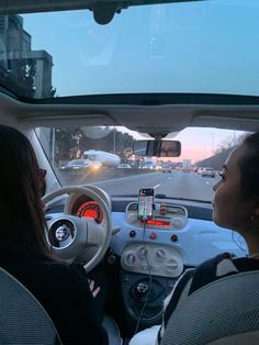 two women sitting in the driver's seat of a car, looking at traffic