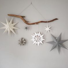 five star ornaments hanging on a wall next to a twig and driftwood branch