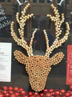 a deer made out of wine corks in front of a window with christmas decorations