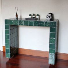 a console table made out of green tiles