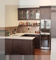 a kitchen with brown cabinets and white counter tops is pictured in this image, there are wine bottles on the shelves