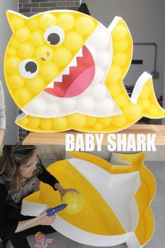 a woman sitting on the floor next to a baby shark balloon