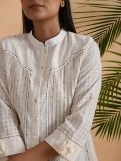 A cotton khadi & chanderi shirt with front placket, 3/4th sleeves, comes with a soft cotton matching slip. Garment measurements (in Inches): Size XS : Bust-34", Waist-36", Hip-Flared Size S : Bust-36", Waist-38", Hip-Flared Size M : Bust-38", Waist-40", Hip-Flared Size L : Bust-40", Waist-42", Hip-Flared Size XL : Bust-42", Waist-44", Hip-Flared Size XXL : Bust-44", Waist-46", Hip-Flared Size 3XL : Bust-46", Waist-48", Hip-Flared Size 4XL : Bust-48", Waist-50", Hip-Flared Length: 30-32", sle Summer Cotton Blouse With Set-in Sleeves, Summer Straight Kurta With Set-in Sleeves, Summer Cotton Kurta With Set-in Sleeves, Traditional Straight Kurta With Pintucks, Long Sleeve Linen Kurta With Chikankari Embroidery, Cotton Long Sleeve Blouse With Pintucks, Spring Cotton Kurta With Pintucks, Off White Cotton Kurta With Cutdana, White Cotton Tunic Shirt