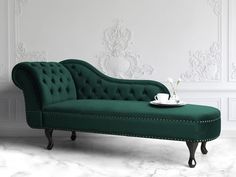 a green chaise lounger with a cup on it in front of a white wall