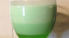 a glass filled with green liquid sitting on top of a table