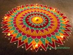 a colorful flower design on the ground with candles in it and some lights around it