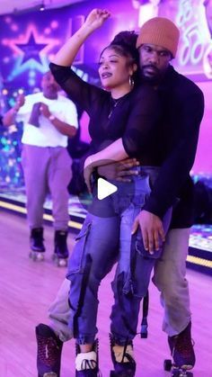 two people riding roller skates on a wooden floor in a room with purple lights