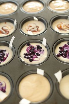 cupcakes with blueberries and cream are in a muffin tin