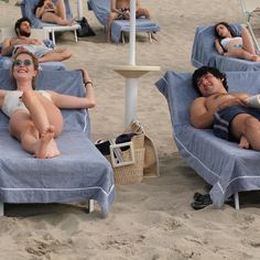 several people lounging on lounge chairs at the beach