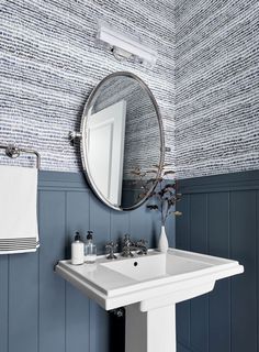 a white sink sitting under a bathroom mirror next to a wall mounted faucet