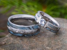 two wedding rings sitting on top of a rock