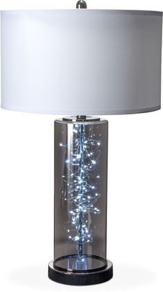 a table lamp with a white shade on it and some lights in the bottom half