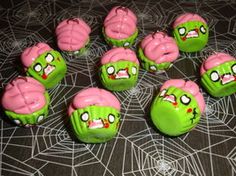 there are many green and pink zombie cupcakes on the table with faces painted on them