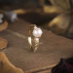 a pearl ring sitting on top of a table next to a book with other items in the background