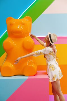 a woman standing next to a giant orange teddy bear