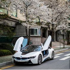 a white car with its doors open parked on the side of the road next to some trees