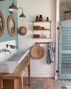 a bathroom with two sinks and some shelves on the wall next to each other in front of a blue door