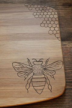 a wooden cutting board with a drawing of a honeybee on it's side