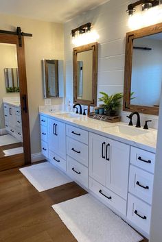 a large bathroom with double sinks and mirrors on the wall, along with white rugs