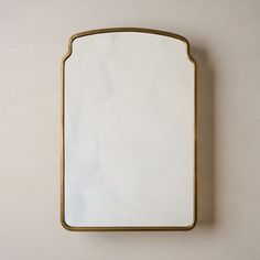 a mirror mounted on the wall with a gold frame and white marble top, against a beige background