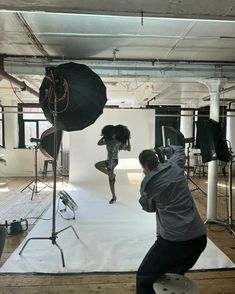 a woman is dancing on a white sheet in front of a camera set up for a photo shoot