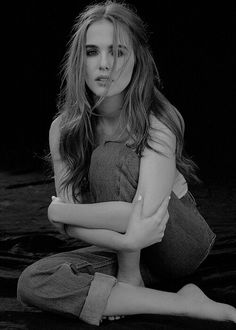 a black and white photo of a woman sitting on the ground with her arms crossed