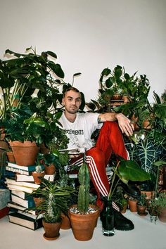 a man sitting on top of a pile of potted plants