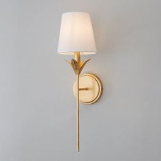 a wall light with a white shade on it's side and a gold finish