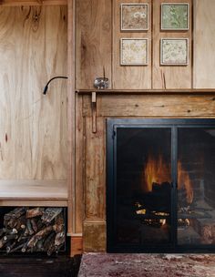 a fire place in a wood paneled room next to a wall with pictures on it