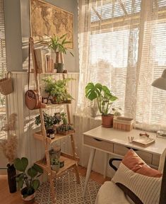 a living room filled with lots of plants next to a white desk and window sill