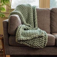 a couch with a blanket on top of it next to a plant in a living room