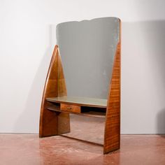 a desk with a mirror on top of it next to a wall mounted shelf in the shape of a triangle