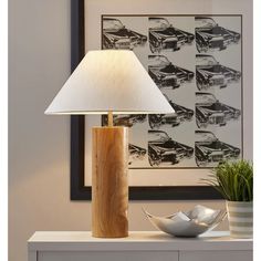 a lamp that is on top of a table next to a bowl and potted plant