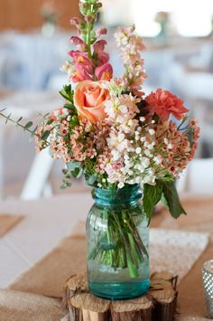 a vase filled with flowers sitting on top of a wooden table next to a piece of wood