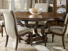 a dining room table with chairs and a bowl of fruit on top of the table