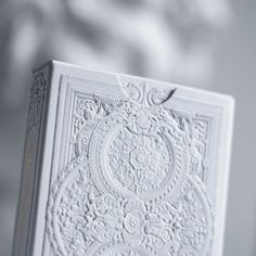 a white card with intricate designs on the front and back cover is shown in this close up photo