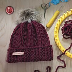 a knitted beanie hat sitting on top of a table next to scissors and yarn