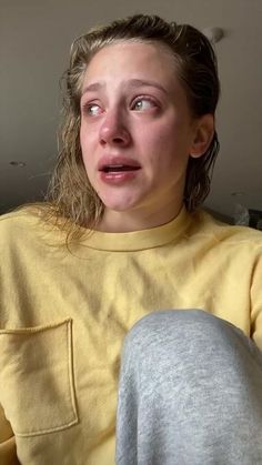 a woman with her mouth open sitting on a couch looking at the camera and making a funny face