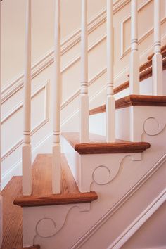 a white staircase with wooden handrails and wood flooring