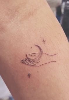 a woman's arm with a small tattoo on it that has a crescent moon and stars