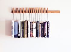 a book shelf with books hanging from it's sides and two strings attached to the wall