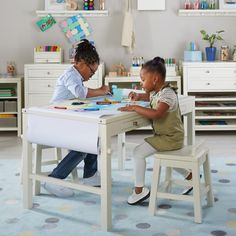 two children are sitting at a table playing with their craft kits in the child's playroom