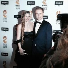 a man and woman standing next to each other in front of a camera on a red carpet