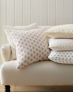 four pillows stacked on top of each other on a white couch in front of a window