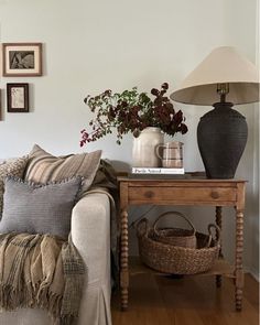 a living room with a couch, table and pictures on the wall above it that are displaying plants