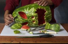 a man is carving a watermelon skull with scissors