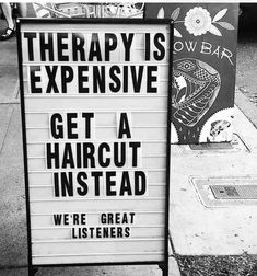 black and white photograph of a sign that says therapy is expensive get a haircut instead we're great listeners