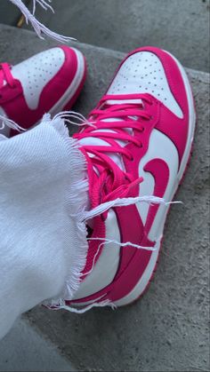 a pair of pink and white sneakers on the ground next to someone's leg